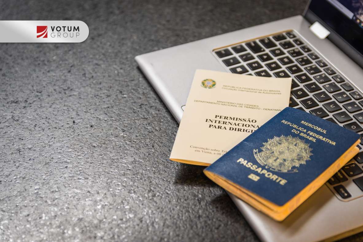 Laptop, na klawiaturze leży paszport i pozwolenie na pracę