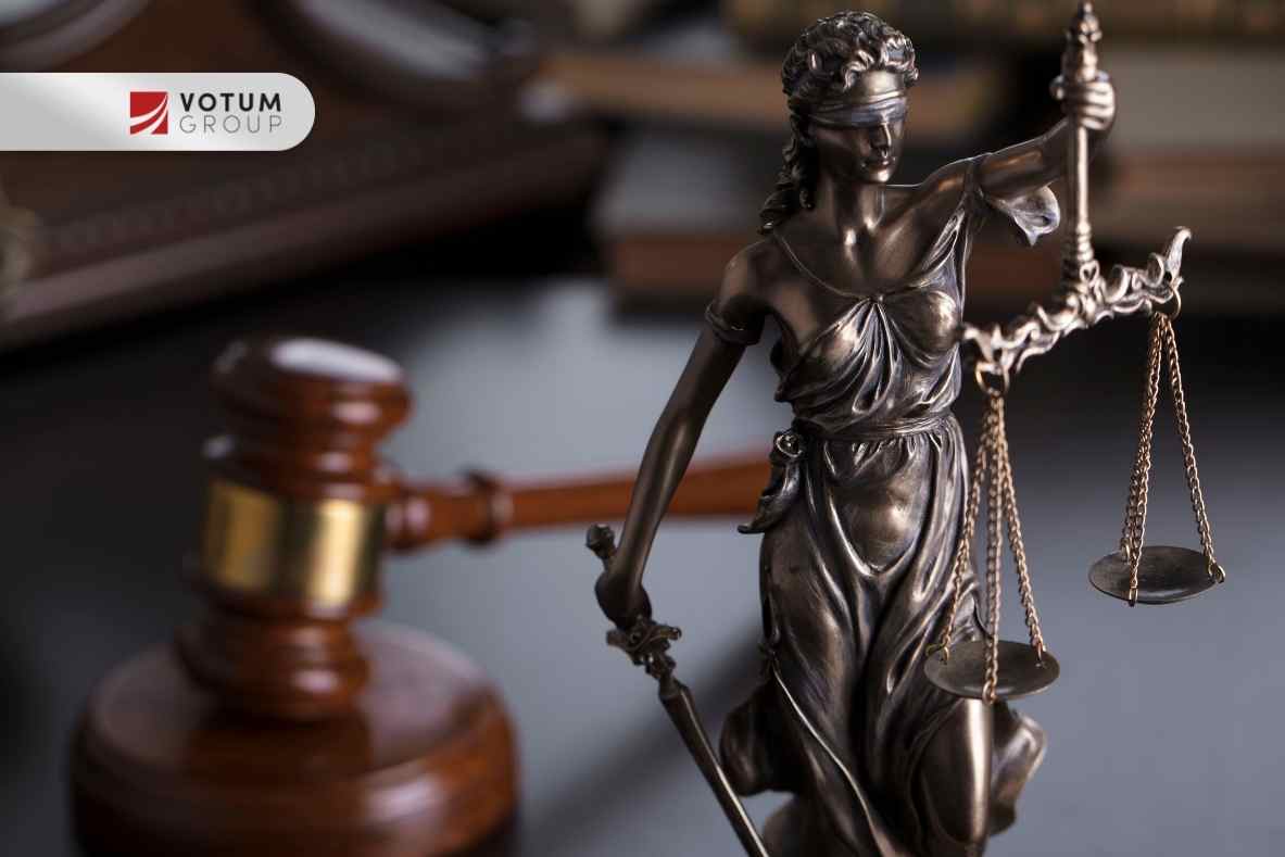 Statuetka Temidy z wagą sprawiedliwości na tle młotka sędziowskiego — symbol prawa i postępowania sądowego w sprawach kredytowych.