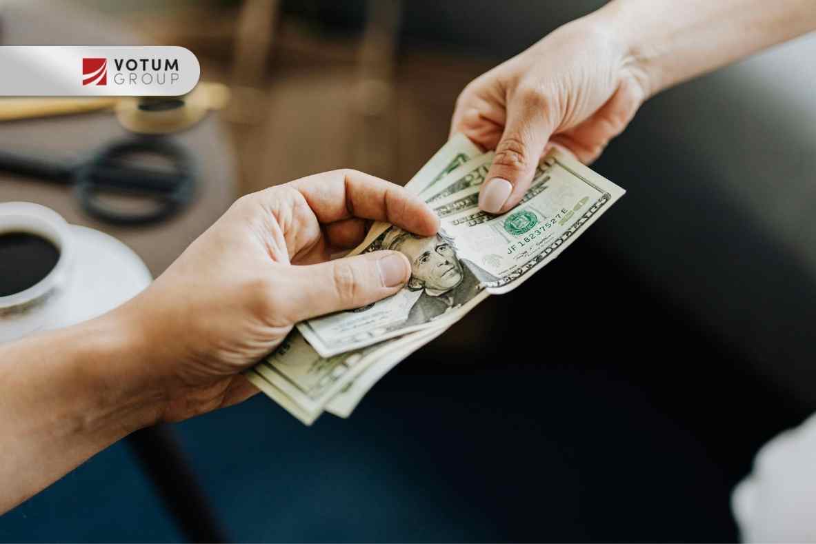 Przekazywanie banknotów dolarowych między dwiema osobami — symbol kredytu walutowego lub rozliczeń finansowych.