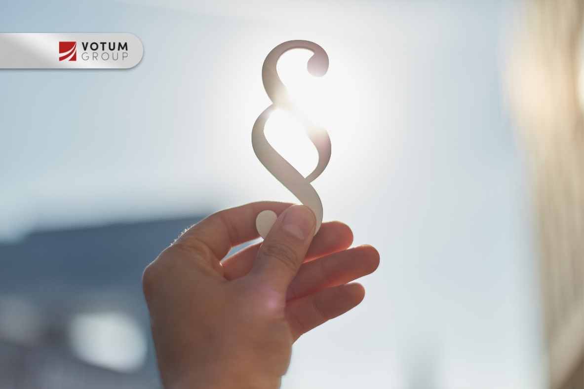 Dłoń trzymająca symbol paragrafu na tle światła, nawiązanie do prawa i spraw sądowych.