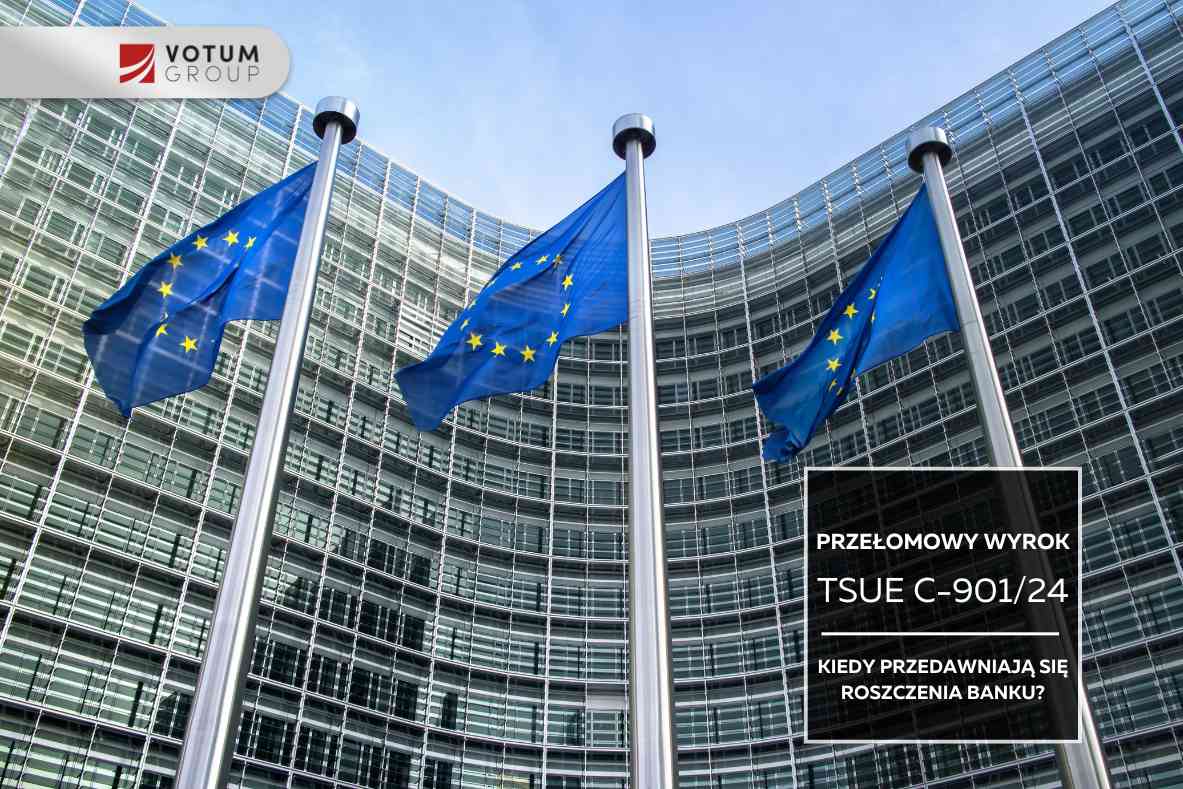 Trzy flagi Unii Europejskiej na wysokich masztach na tle nowoczesnego, przeszklonego budynku o zaokrąglonej fasadzie.